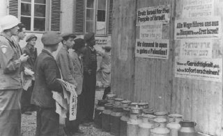 بازماندگان یهودی در اردوگاه آوارگان مشغول نصب اعلامیه...