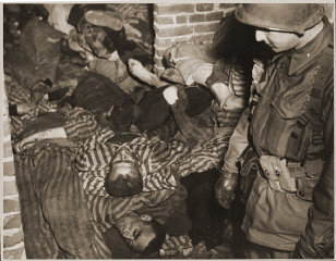 An American soldier views the bodies of prisoners piled...