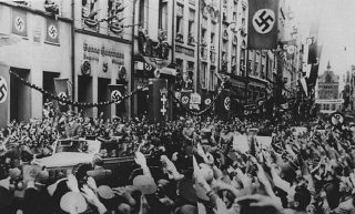 Adolf Hitler (debout à l’avant de la voiture) entre...