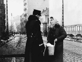 A Polish policeman searches the bag of a Jewish resident...