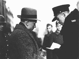A Polish policeman checks the papers of a Jewish resident...