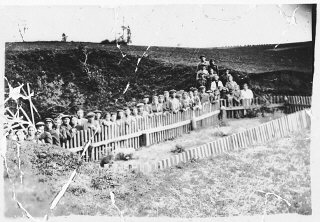 解放后不久，比耶尔斯基（Bielski）游击队成员在乱葬岗遗址前留影。