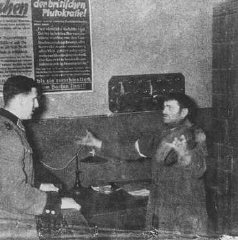 A German policeman interrogates a Jewish man accused...