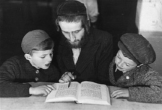 Bambini studiano un testo di religione con un maestro...