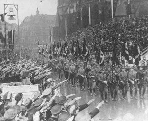 Hitler reviews a parade celebrating the reintegration...