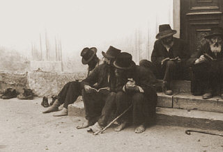 Jewish men sitting on the steps of a synagogue.